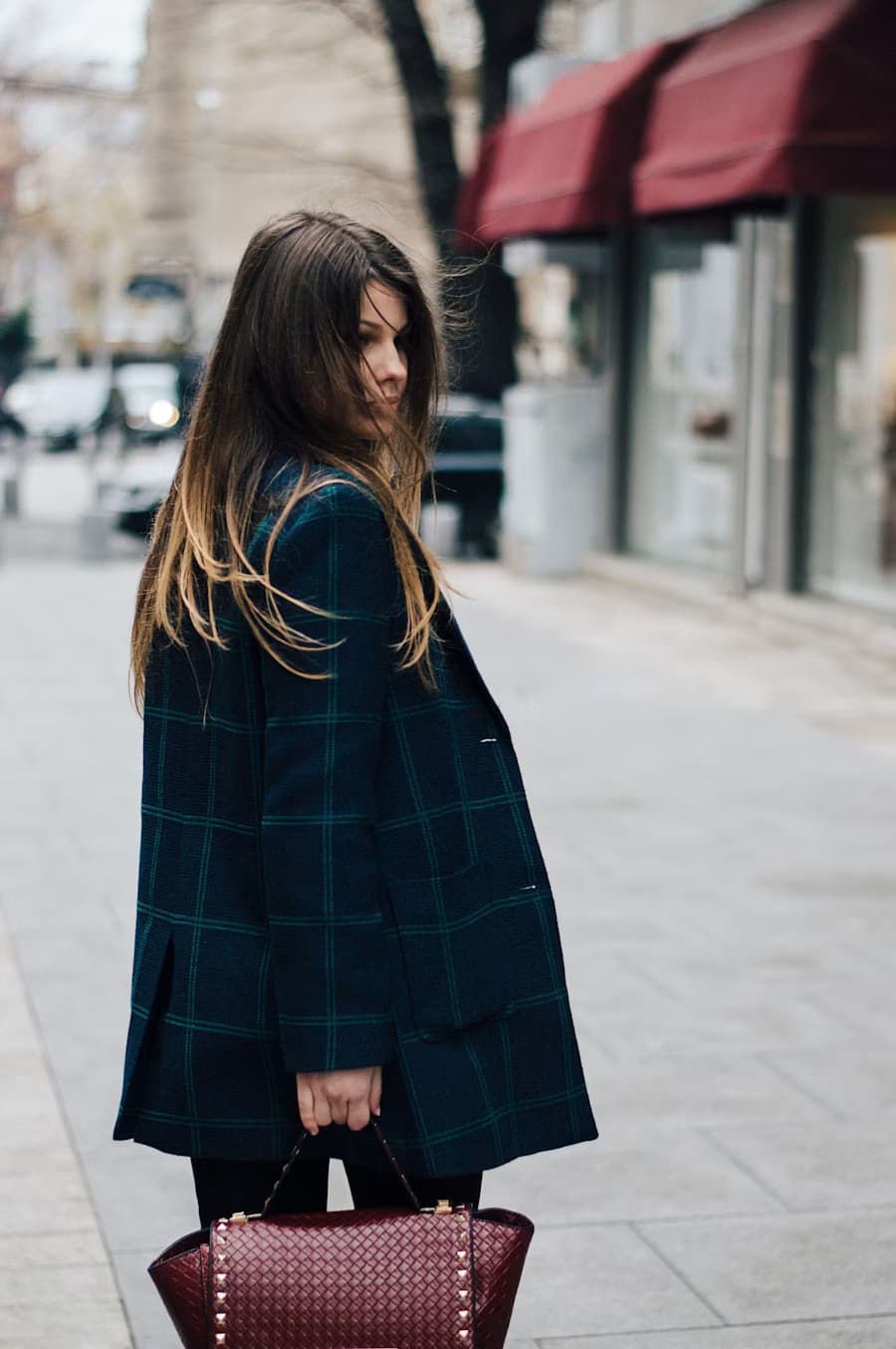 A woman in a structured coat walking on a city street